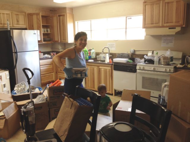 Lisa is washing dishes and putting them in the new cupboards. They got all dusty in the construction!